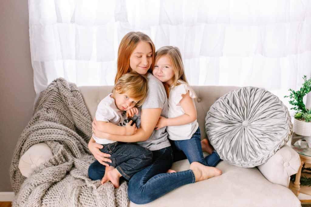 mother cuddling children on couch during lifestyle motherhood photoshoot