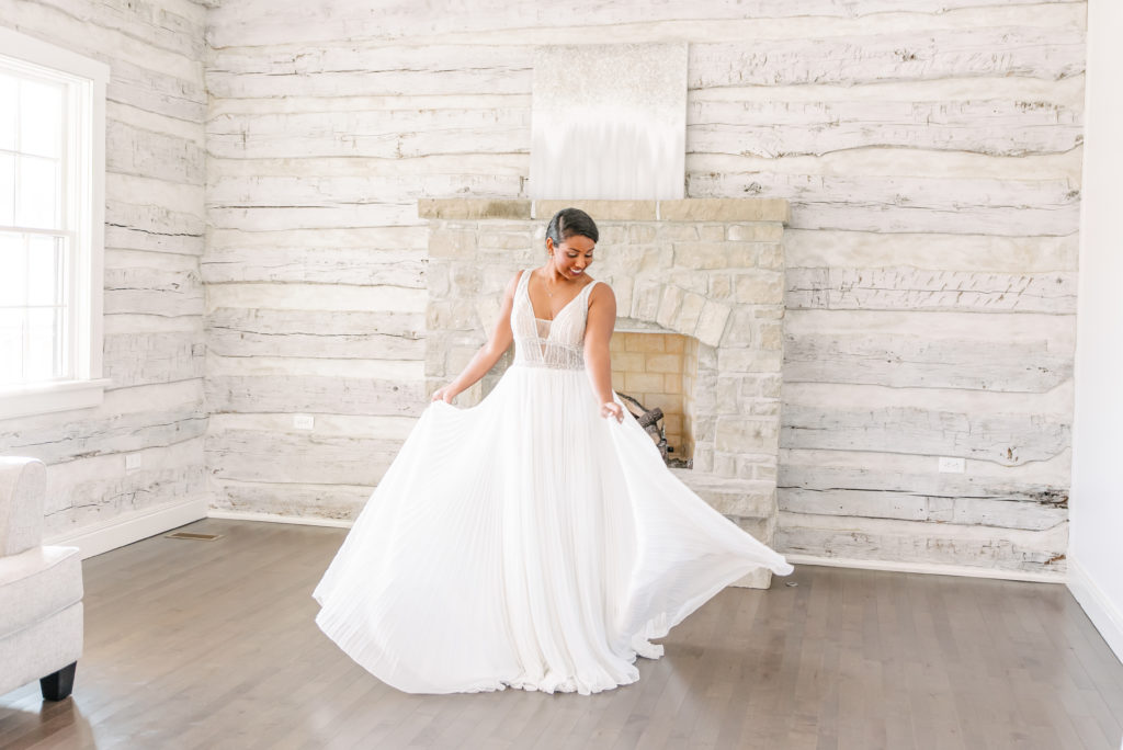 A bride twirls in her wedding dress in a white bridal suite.