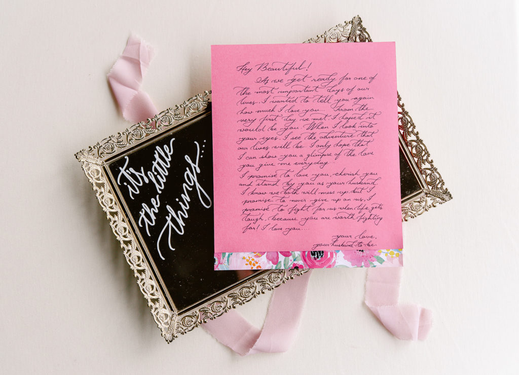 A handwritten love letter from a groom to his bride on their wedding day lays on top of an ornate tray.